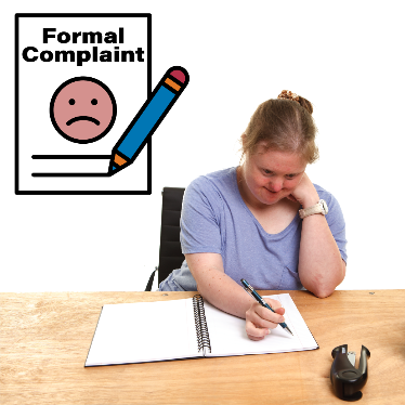 A woman writing on a piece of paper with a formal complaint document next to her