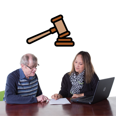 2 people looking at a document and a computer. There is a gavel above them